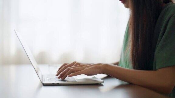 女人的手在家里的电脑笔记本键盘上打字