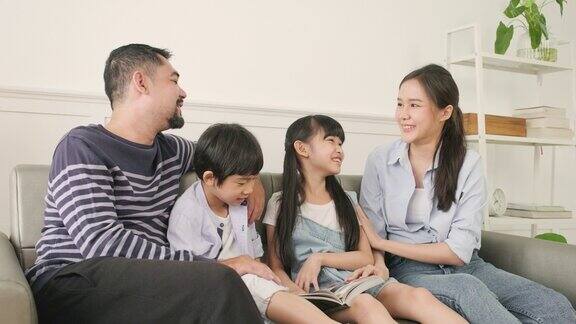 亚洲家庭幸福地一起在白色客厅的沙发上读书