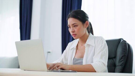 年轻的亚洲女性在家里用笔记本电脑工作