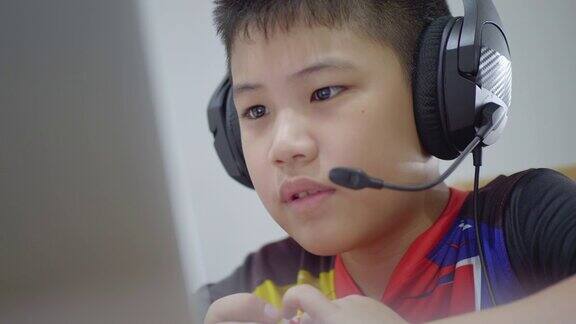 新常态亚洲男孩上网学习看着屏幕笔记本电脑开心地笑在家里开心地笑技术教育