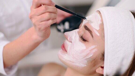 美容专家用刷子为女性涂抹面膜