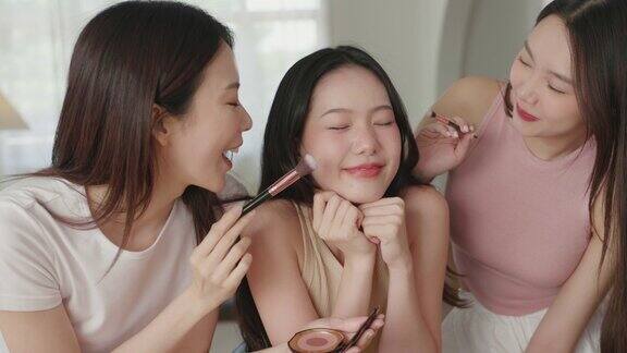 美丽的亚洲女人喜欢在朋友的脸颊上涂腮红