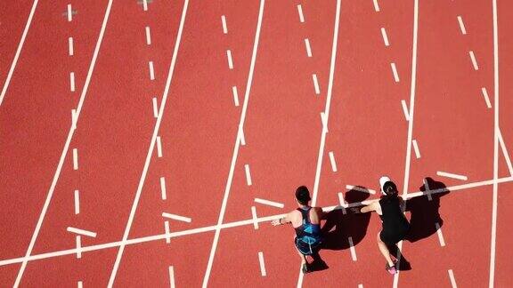 无人机视角体育亚洲华人夫妇运动员上午在田径场跑步