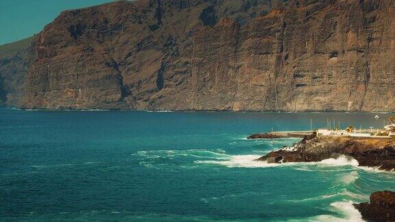 在加那利群岛特内里费岛的阿坎蒂拉多斯岩石海岸线上清澈的蓝色海洋景观慢动作的海浪冲击着悬崖