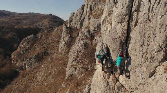 两位女性攀岩者正在爬上悬崖
