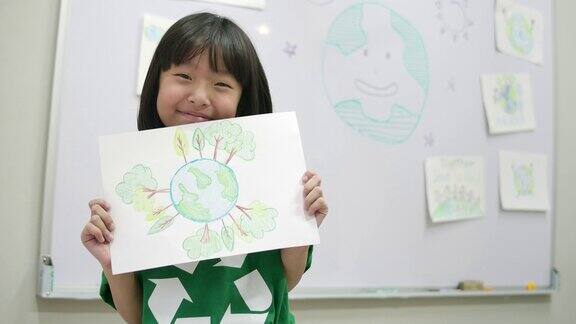 亚洲小女孩的肖像与绿色生态t恤拿着她的图纸拯救世界计划志愿、自然、教育理念