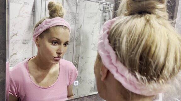 中年妇女摸着脸看着镜子里的倒影