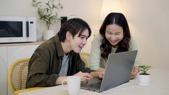 微笑的年轻情侣在笔记本电脑上上网