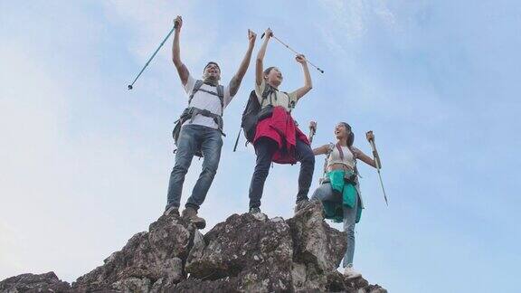 一群年轻的徒步旅行者在山顶上举起手臂庆祝他们的成功