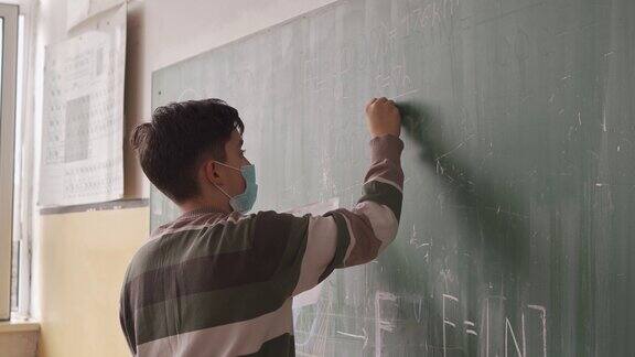 一名学童戴着防护口罩在黑板前研究物理