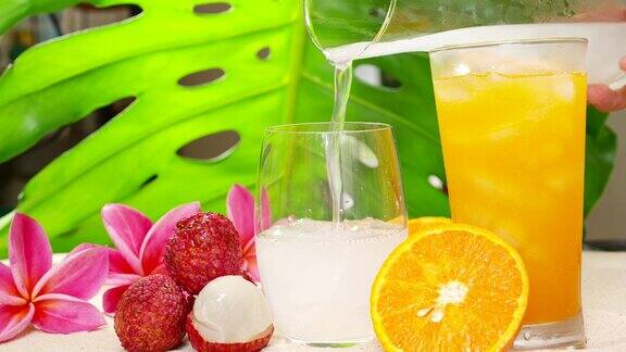 荔枝汁倒入玻璃杯旁边是冰橙汁玻璃杯