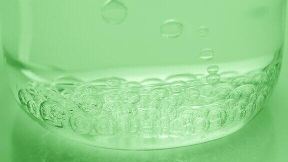 气泡下沉到烧杯底部绿色背景上有水