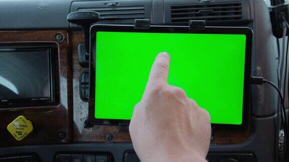 特写镜头卡车里的司机手里拿着一个绿色屏幕的平板电脑