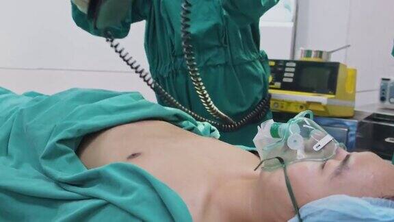 医院手术室的一组医生亚洲专业的外科医生和护士团队为重症监护患者实施心肺复苏术并在手术中使用除颤器电击心脏