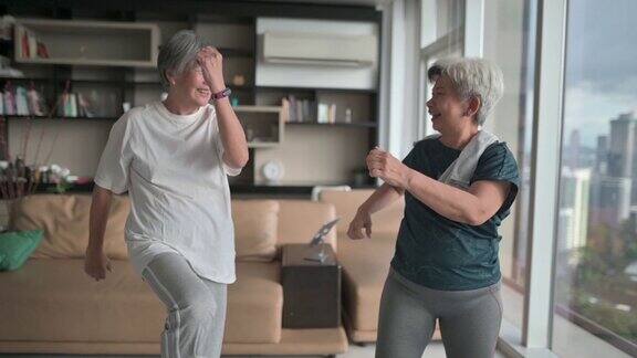 亚裔中国年长女性朋友在公寓客厅享受家庭锻炼在晚上