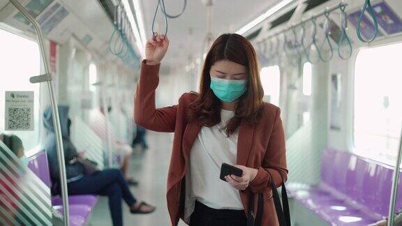 女商人坐在火车上戴着防护面具用着智能手机