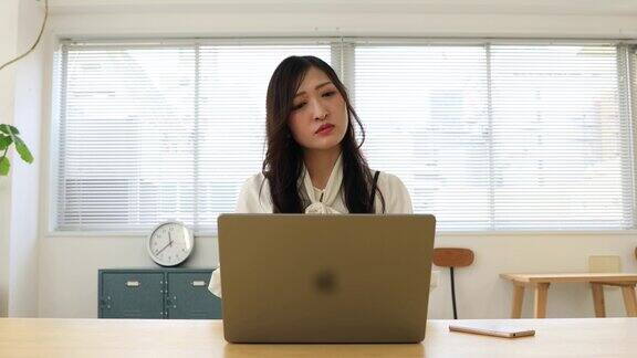 一位忧心忡忡的日本妇女在小办公室里远程工作