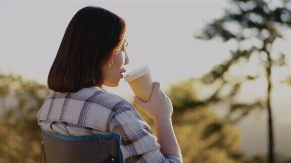 清晨女人在户外的山上拿着咖啡杯放松