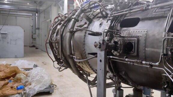 劳斯莱斯的飞机引擎正在修理中拆卸工具和扳手摆放在地板上喷气发动机喷嘴燃料线喷气发动机维修涡轮喷气发动机的维修特写镜头