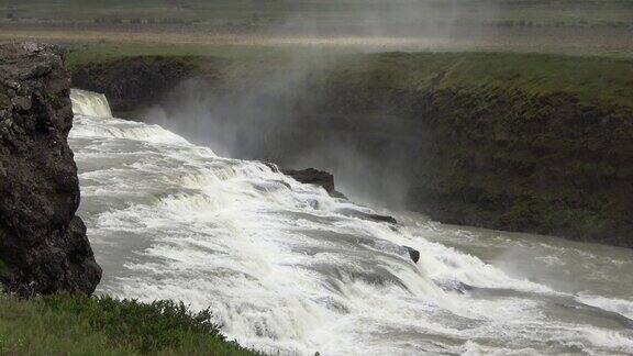 奇妙的瀑布在冰岛的景观与岩石和草