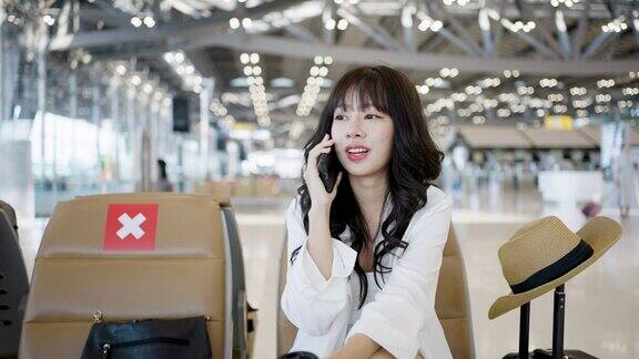 一名亚洲年轻女子在机场候机楼边喝咖啡边使用智能手机