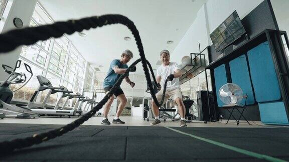 亚裔华人年长私人教练鼓励年长男子在健身房练习跳绳