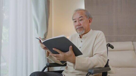亚洲老年残疾人脸上带着快乐享受居家护理一个成熟的老人坐在轮椅上手里拿着书在医院等待医生的治疗