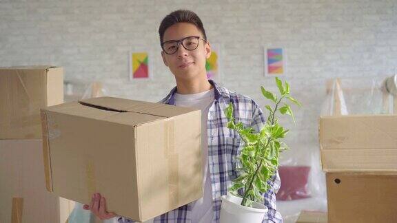 积极的年轻西安男子戴着眼镜与一朵花在他的手一个盒子搬到一个新的公寓