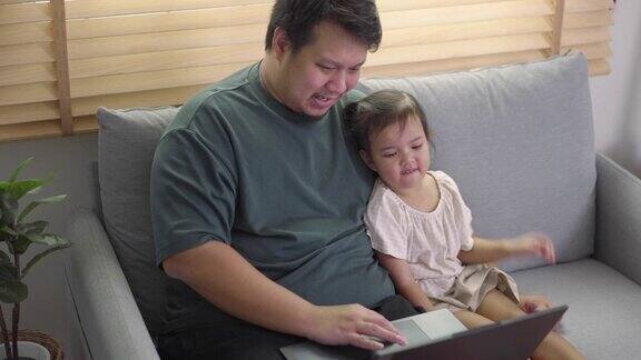 幸福的家庭父亲和女儿在客厅用笔记本电脑看视频