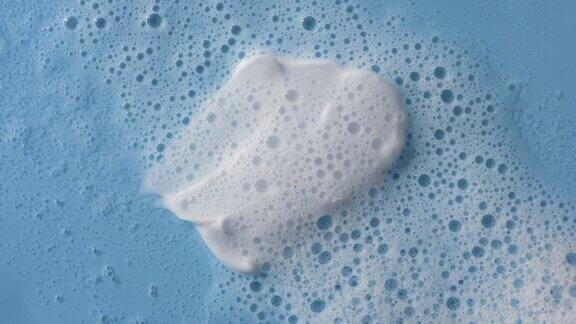 白色奶油涂抹在蓝色背景覆盖的泡沫水