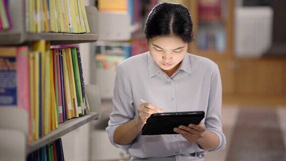 在亚洲的大学图书馆一名亚洲女性正在图书馆用平板电脑搜索互联网