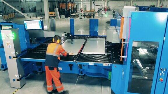 使用工业设备工作的工人操作员正在把铝板放到工厂机器上