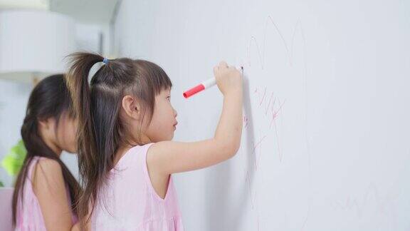 亚洲年轻的兄弟姐妹孩子女孩喜欢在客厅的白色墙壁上油漆可爱的小朋友们在假期的时候在家里开心地画画、涂色享受着创意活动