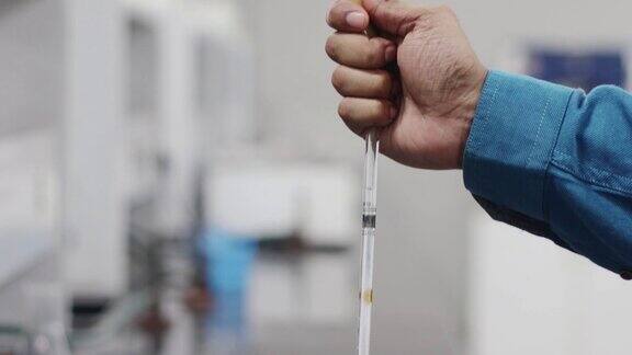 一个近距离的视频一只手挤压玻璃吸管的橡胶乳头在一个化学实验室的玻璃管中抽取化学物质