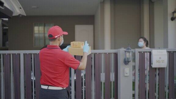 4k慢动作视频一名身穿红色制服的男性快递员寄包裹盒子在寄给收件人之前喷洒清洁酒精新标准