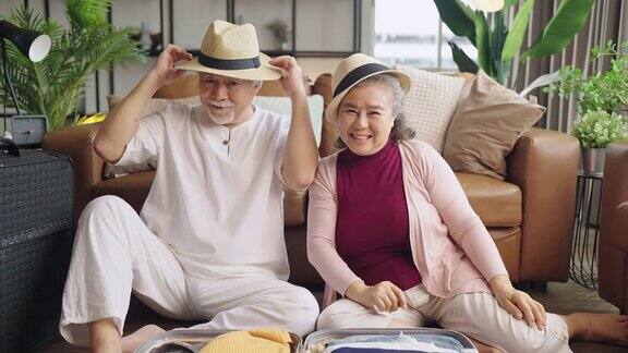 老亚洲的老夫妇收拾着布行李一起旅行幸福亚洲的老年退休的成熟成人享受在客厅地板上一起整理布准备旅行后封锁