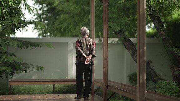 在日本花园的阳台上散步的老年妇女