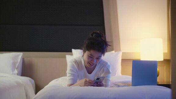 度假旅游概念有吸引力的亚洲女性女人休闲布料与笔记本电脑在酒店床上工作快乐漂亮的女性在家工作