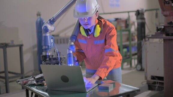 女工程师用平板检测系统软件控制和检测智能汽车工业中手臂的自动焊接