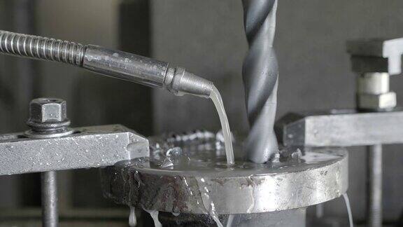 近距离钻孔机钻孔厚钢和润滑与水在工业工厂慢动作