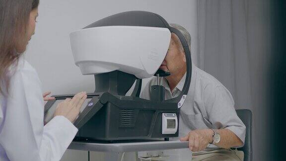 图为一位女验光师在一家眼镜店用医疗器械检查老年男性的视力