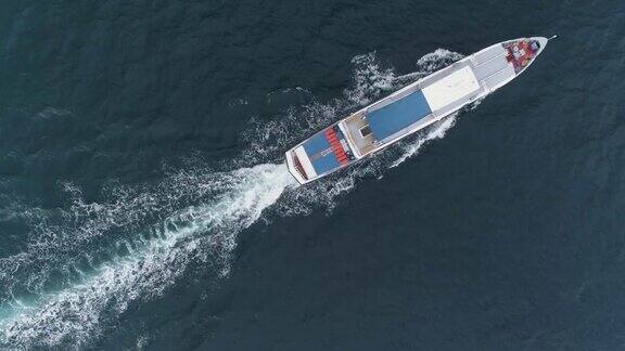 一艘白色的小游船在海上航行无人驾驶飞机盘旋空中垂直从上到下的视图