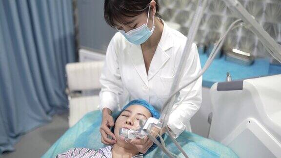 亚洲华人妇女在医疗中心接受激光面部治疗皮肤年轻化美容外科医生给予分式CO2激光皮肤治疗女性病人