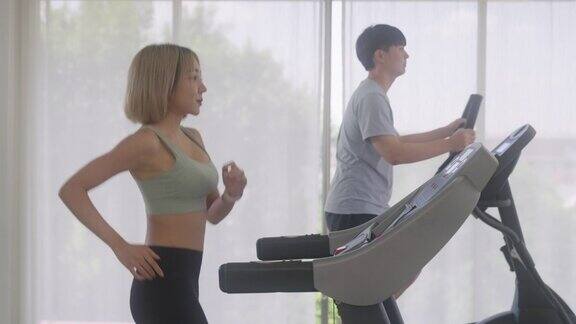 迷人的亚洲女孩在健身房的跑步机上跑步