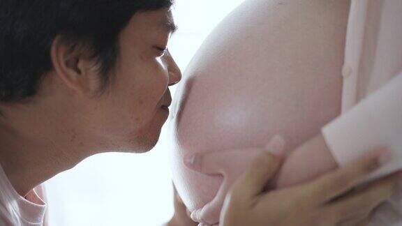 爸爸在妈妈肚子上亲吻宝宝感到爱和幸福