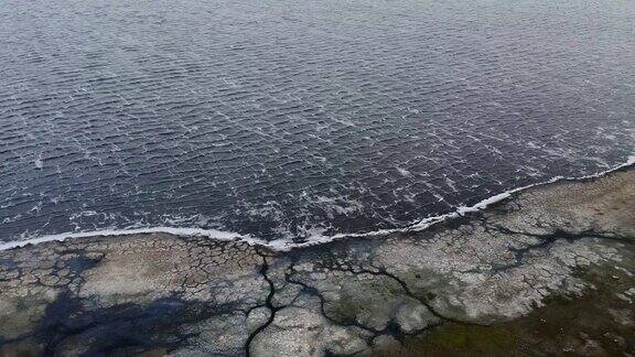 鸟瞰图在暴风雨中飞过海岸线镜头移向右侧上方是布满岩石的海岸和泡沫的海浪
