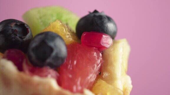 新鲜多汁的水果沙拉和蓝莓在一个华夫饼篮子旋转在粉红色的背景微距拍摄素食食品