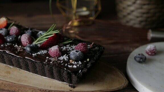 矩形挞巧克力芝士蛋糕与新鲜浆果美味的庆祝甜点以木桌为背景