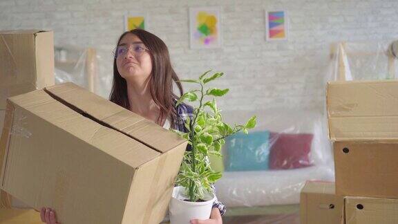 积极的年轻西安女人在眼镜与花和一个盒子在他的手搬到一个新的公寓