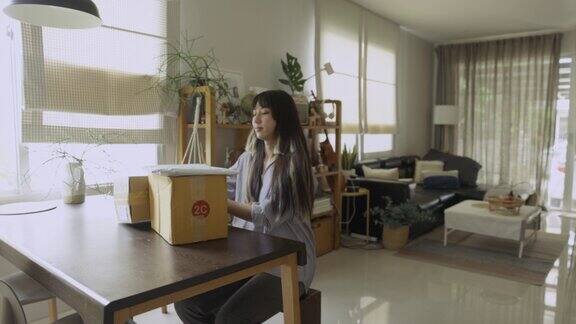 一名年轻的亚洲女子从网上购物收到产品盒